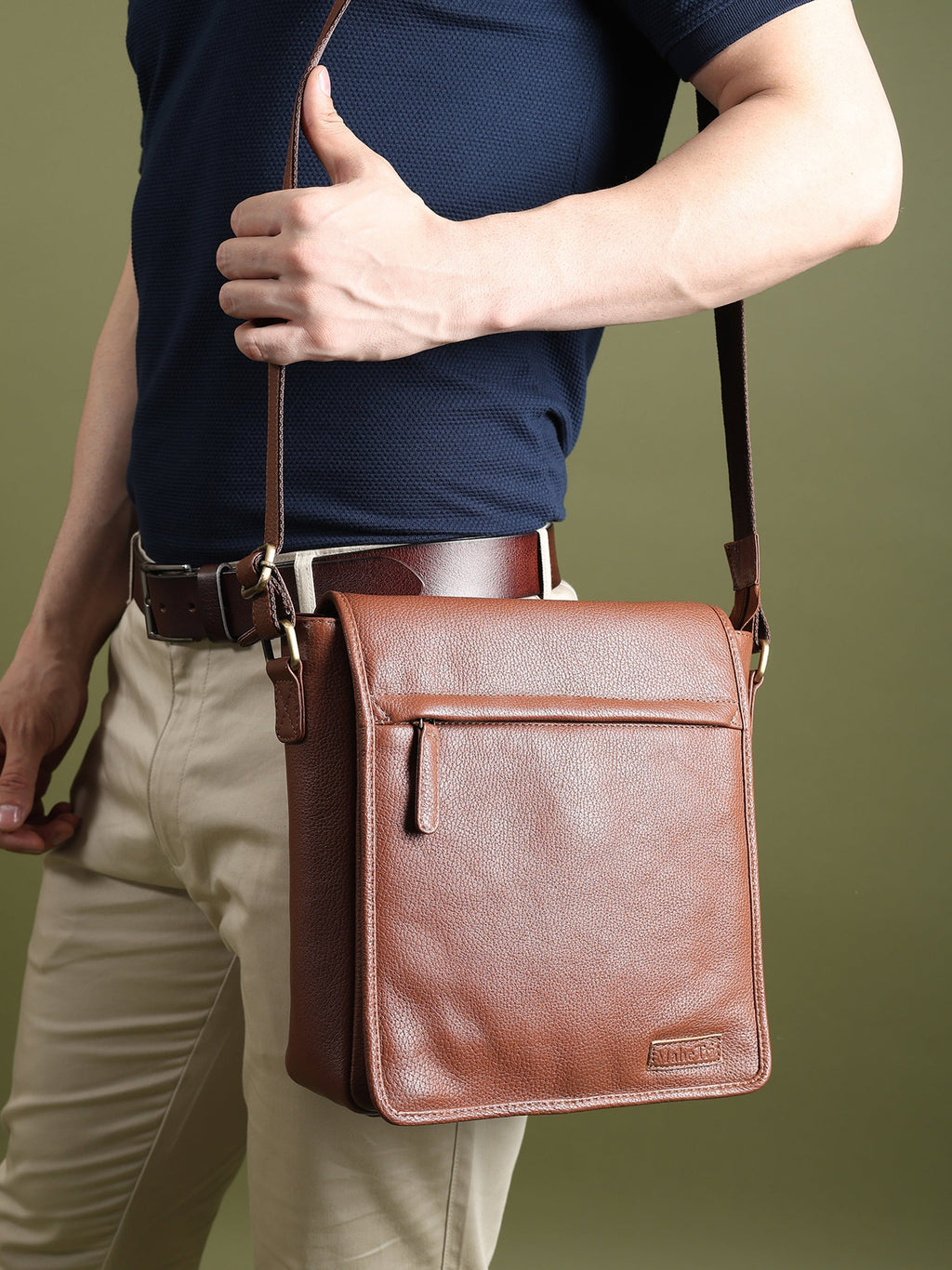 Brown leather crossbody bag worn across the chest with adjustable strap