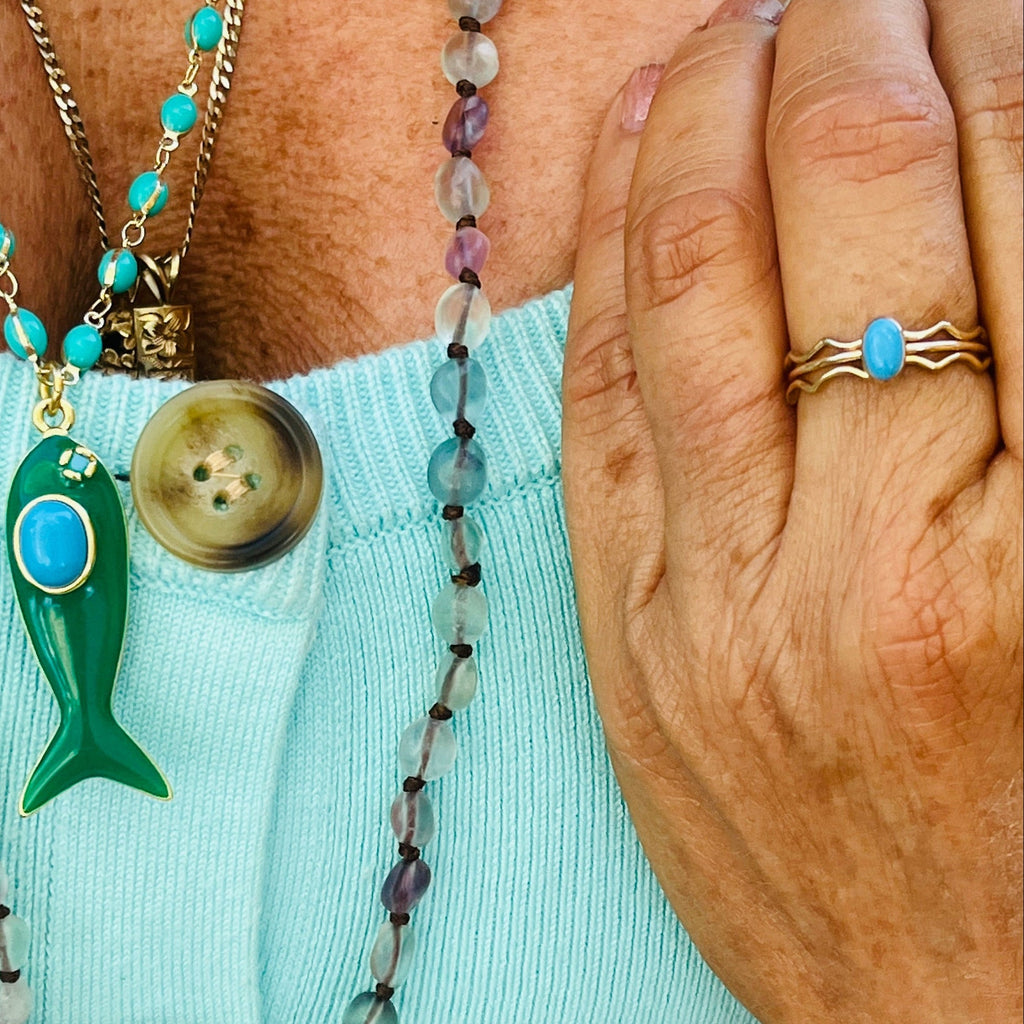 Gold-tone ring with oval turquoise cabochon on a wave-style band