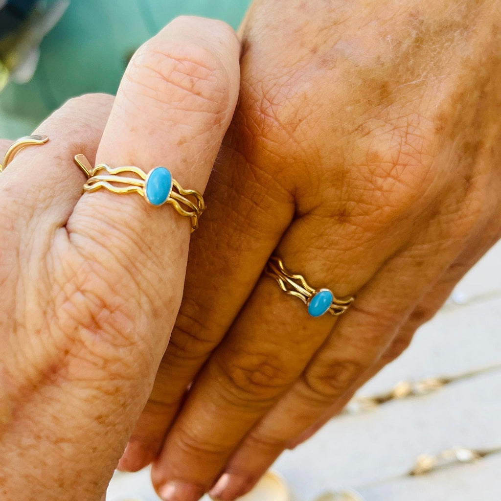 Gold-tone wave ring with oval turquoise cabochon on two fingers