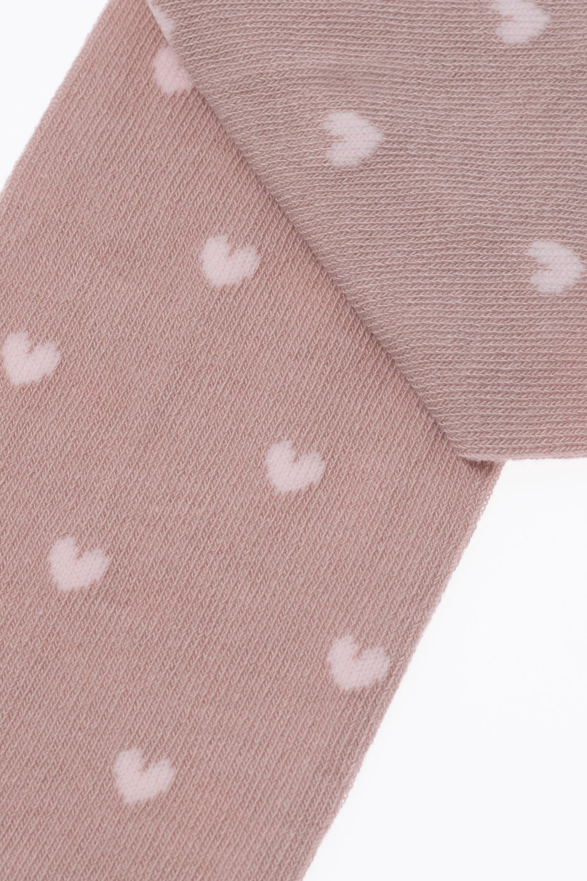 Light pink kids cotton tights with small white hearts, ribbed knit texture close-up