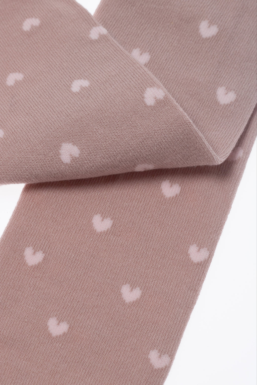 Light pink kids cotton tights with small white hearts, folded fabric detail close-up