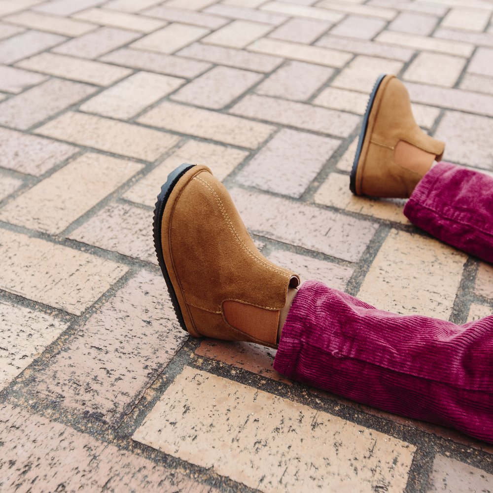Kids brown Chelsea boots on a brick sidewalk with rubber tread sole