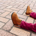 Kids brown Chelsea boots on a brick sidewalk with rubber tread sole