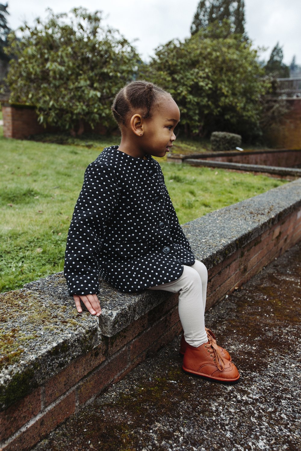 Brown lace-up toddler shoes on steps near brick wall
