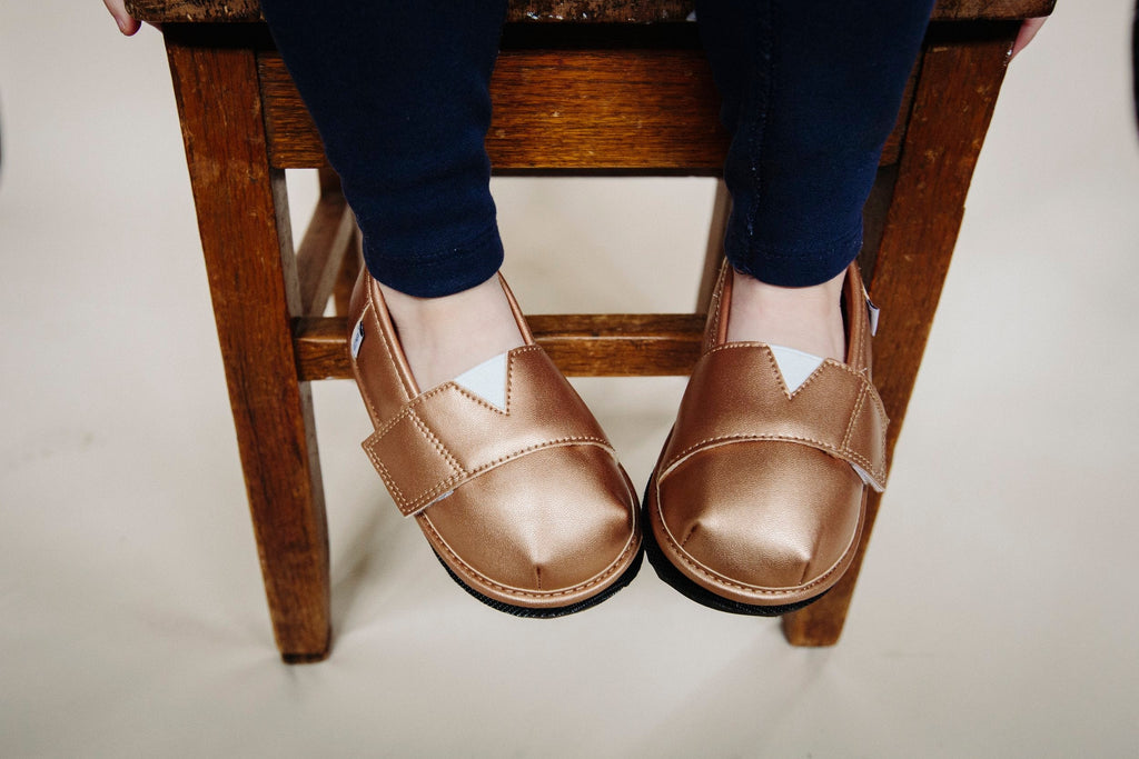 Gold metallic slip-on shoe topper on feet with two hook-and-loop straps