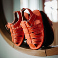 Orange kids sandals close-up showing stitched panels and double hook straps