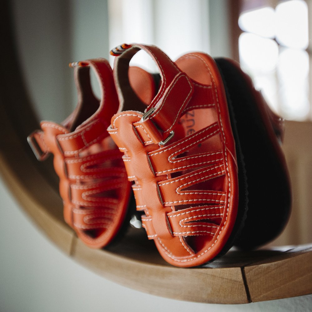Orange kids sandals close-up showing stitched panels and double hook straps