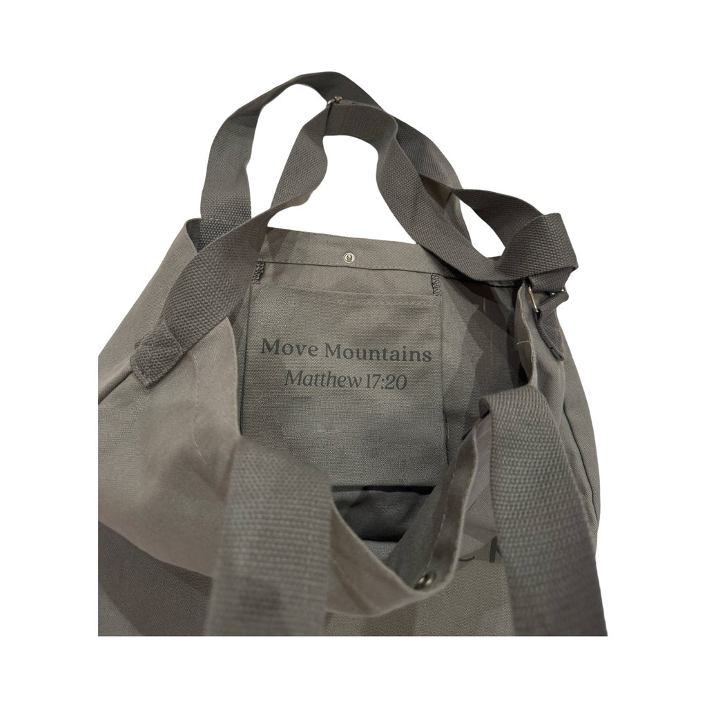 Gray canvas tote bag open with interior pocket showing Move Mountains text
