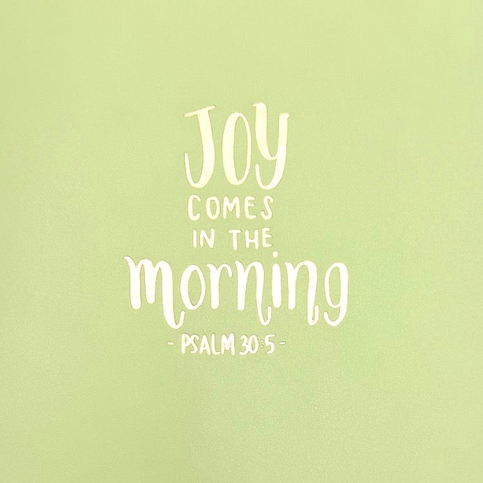 Close-up lime green journal cover with 'Joy comes in the morning' quote