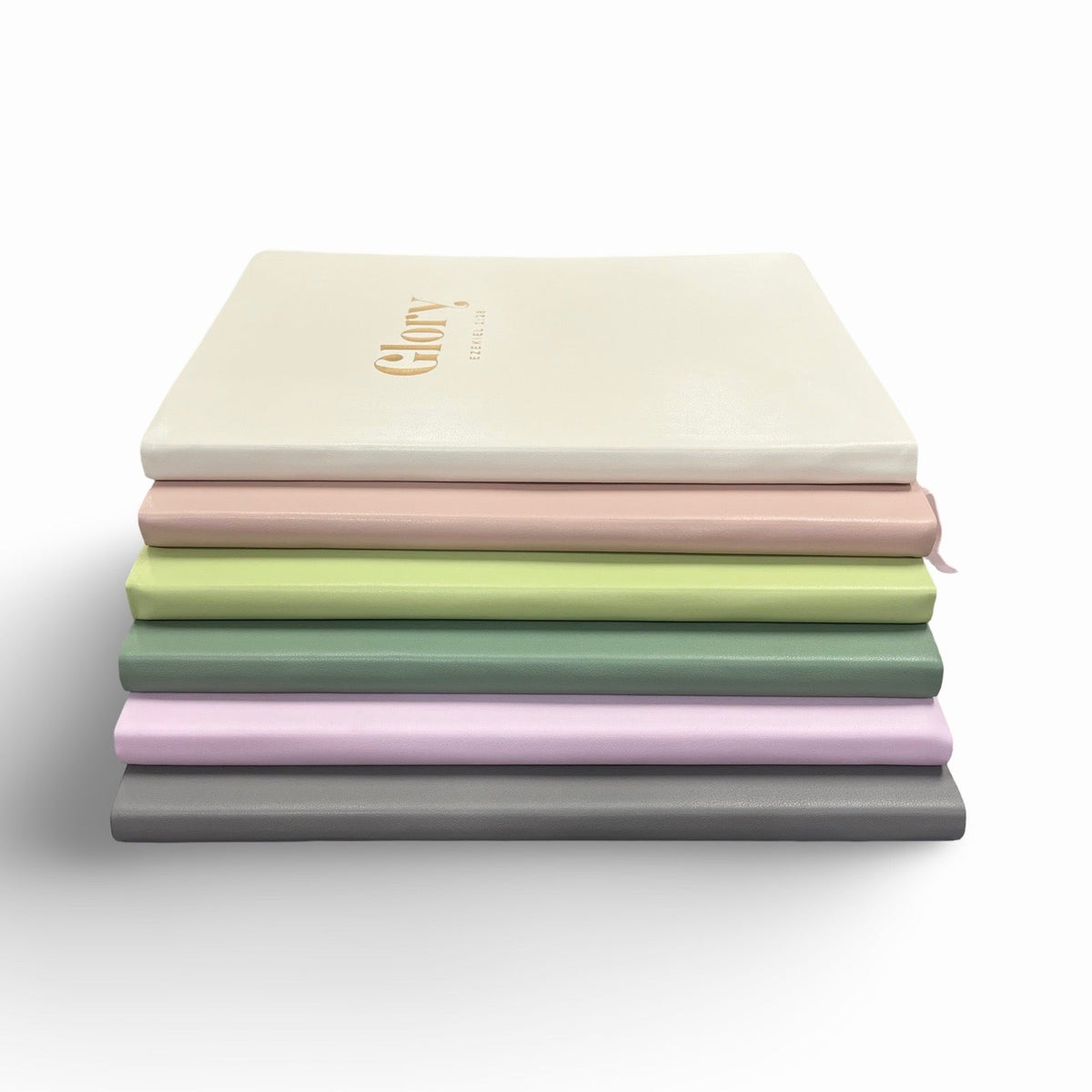 Stack of soft leather journals in white, blush, mint, purple, and gray with gold logo
