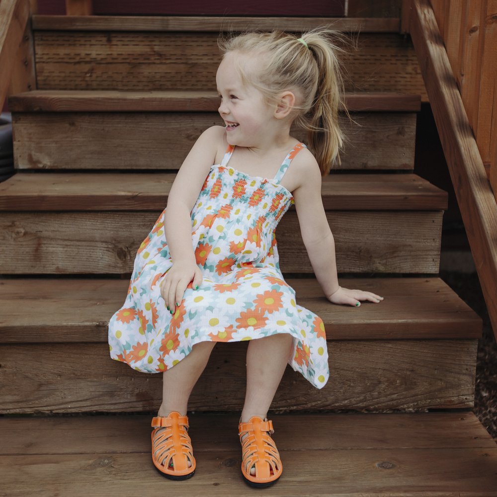 Orange kids sandals on a child, open toe and double hook-and-loop straps