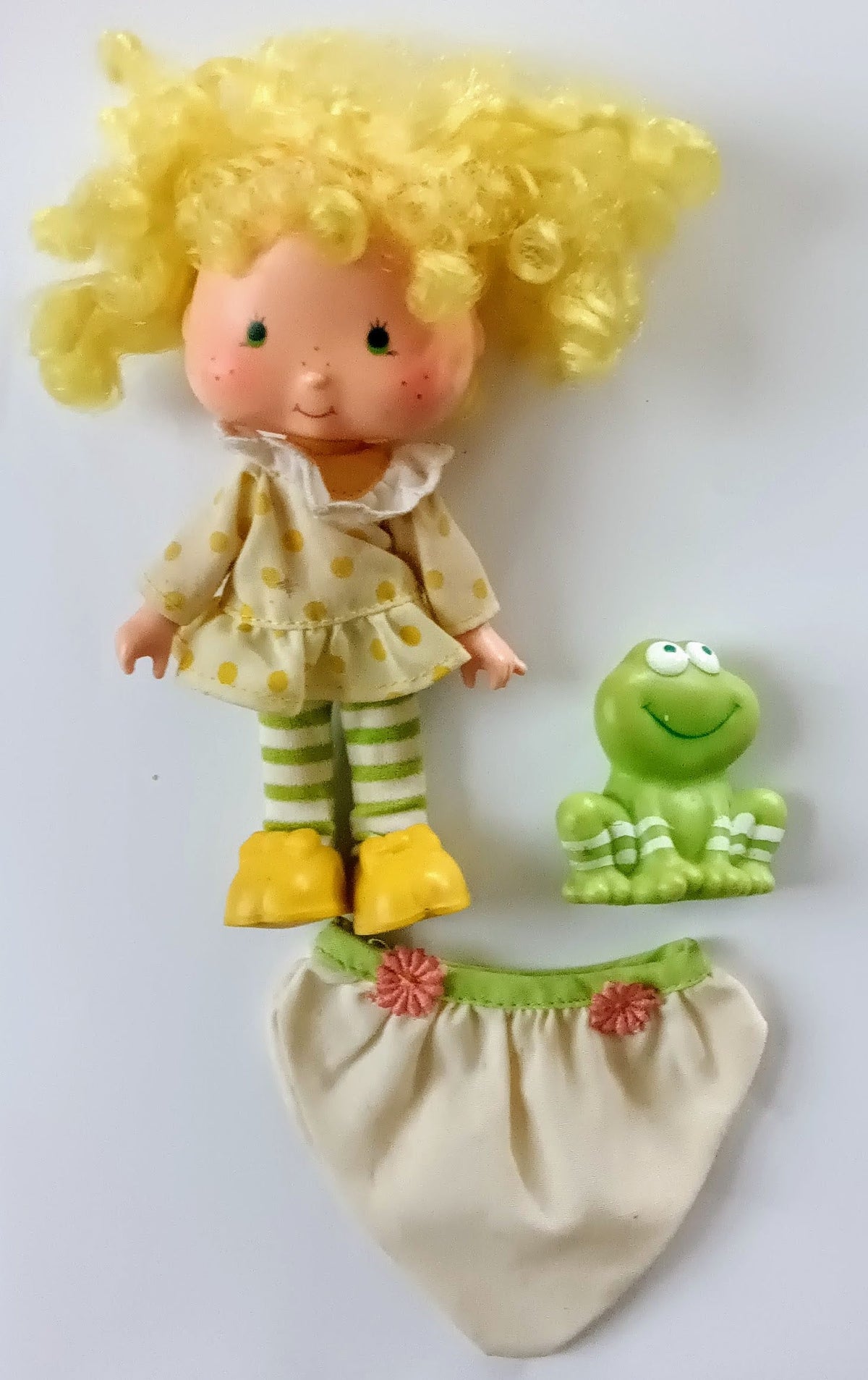 Lemon-themed doll with yellow bonnet, striped pants, and green frog companion