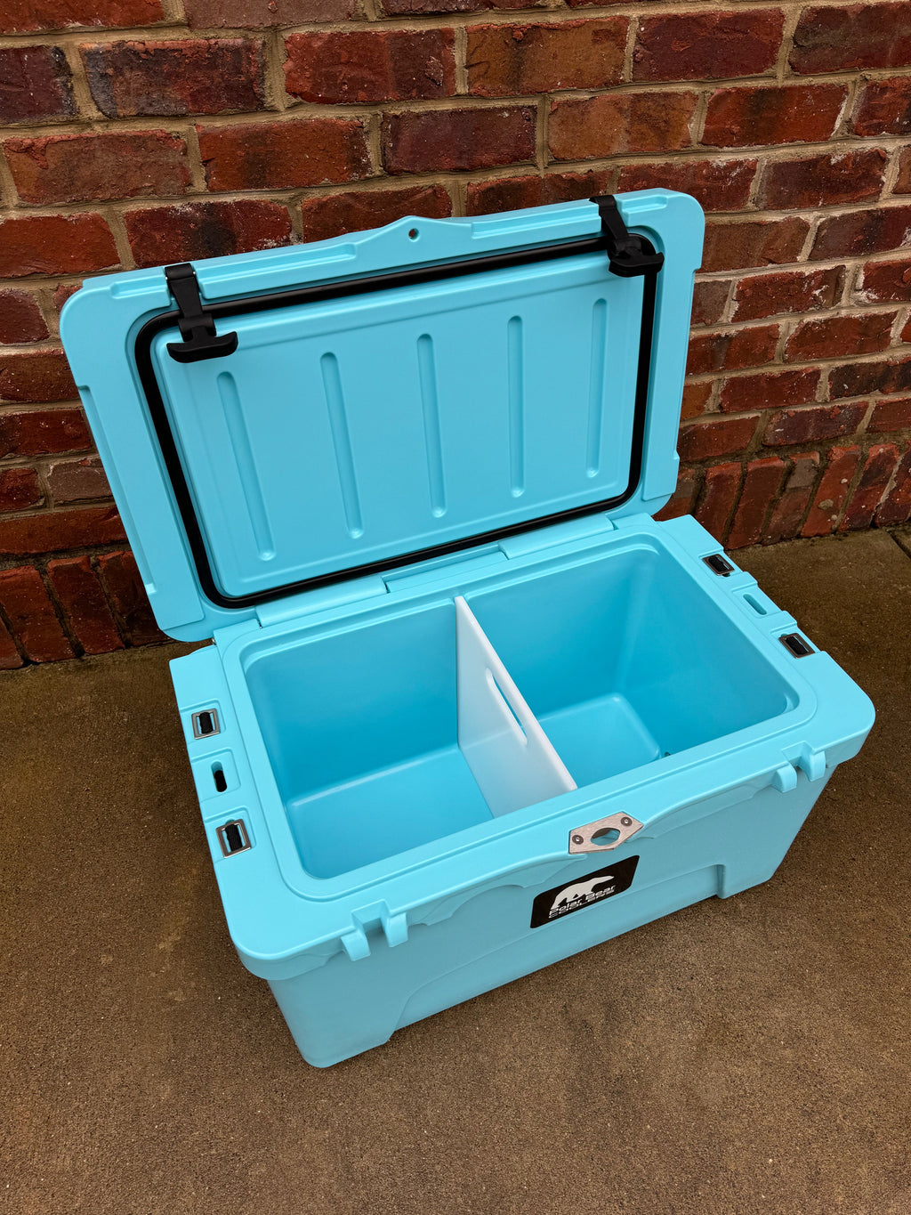 Light blue hard cooler open showing large insulated basin and side handle bracket
