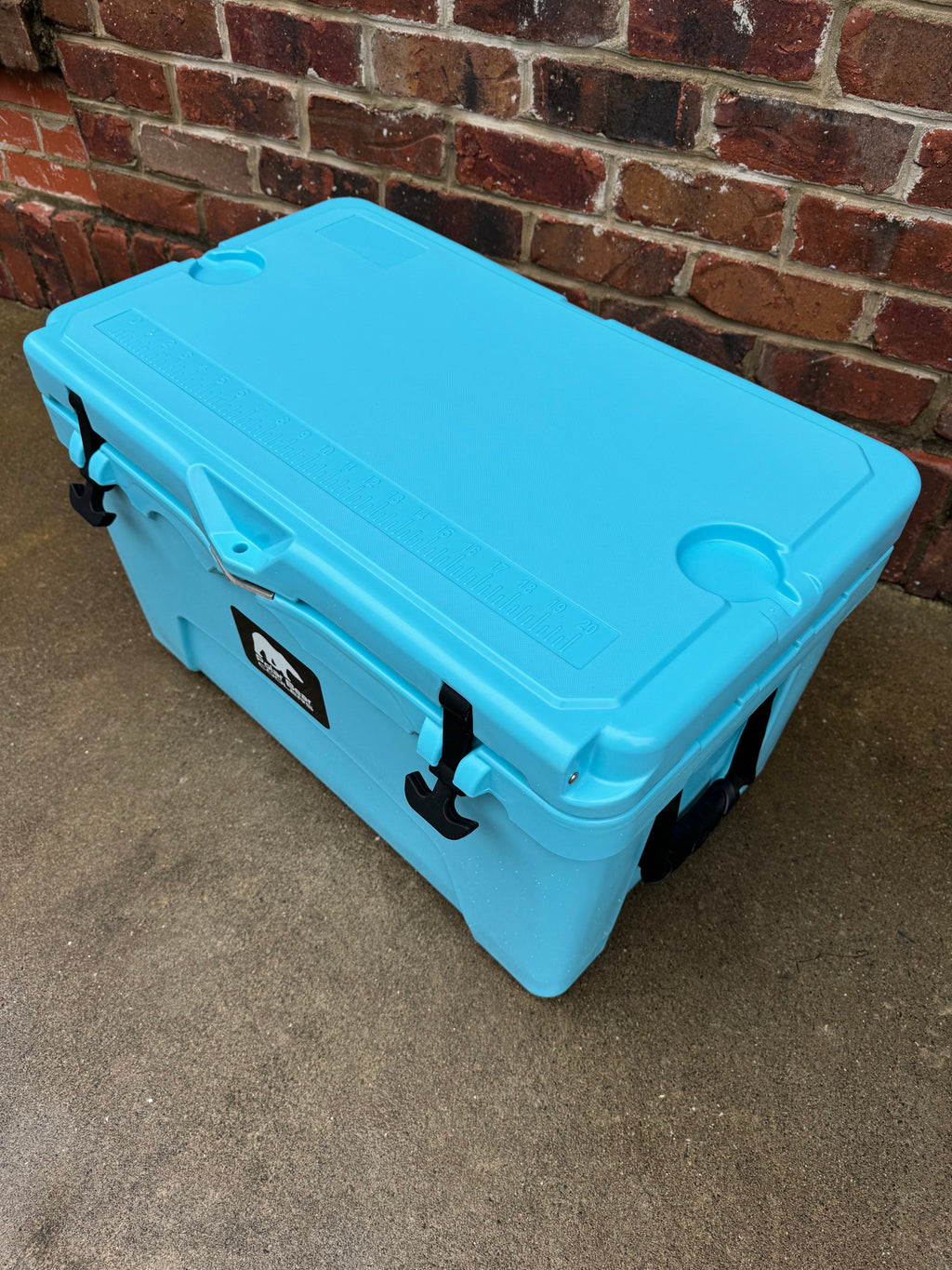 Light blue hard cooler with side latches and black rubber corner protectors
