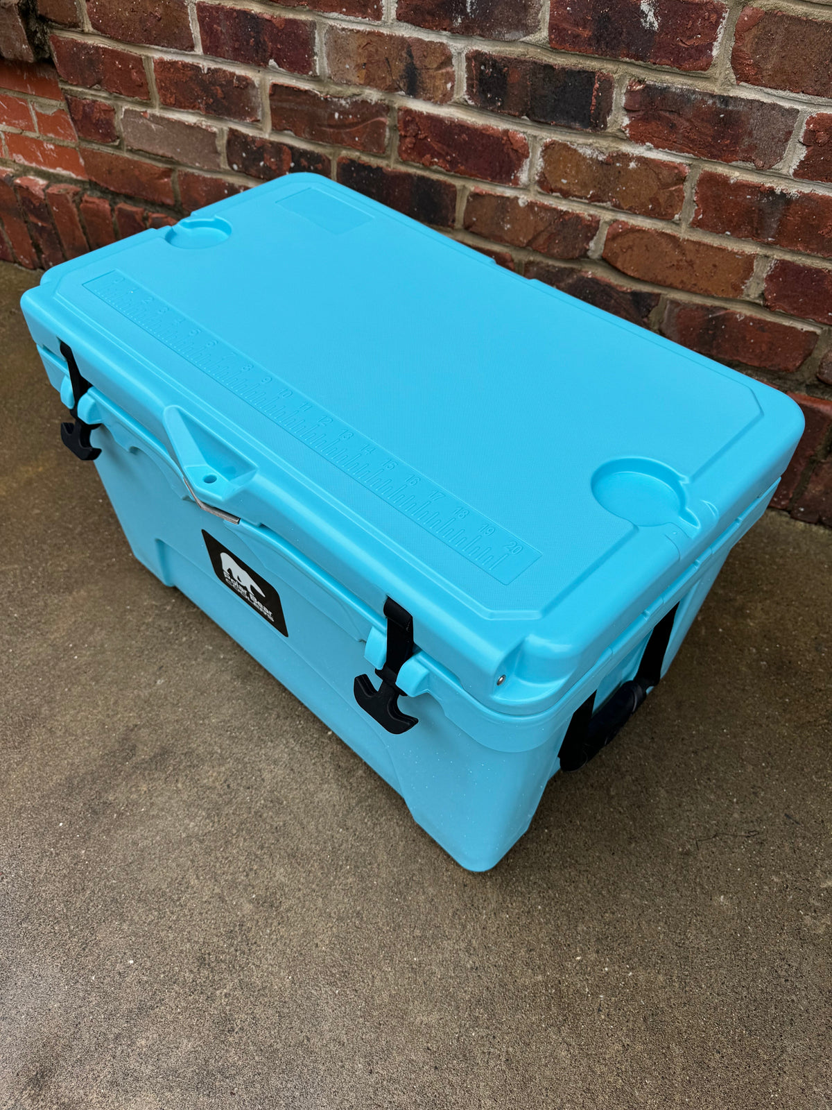 Light blue hard cooler with side latches and black rubber corner protectors