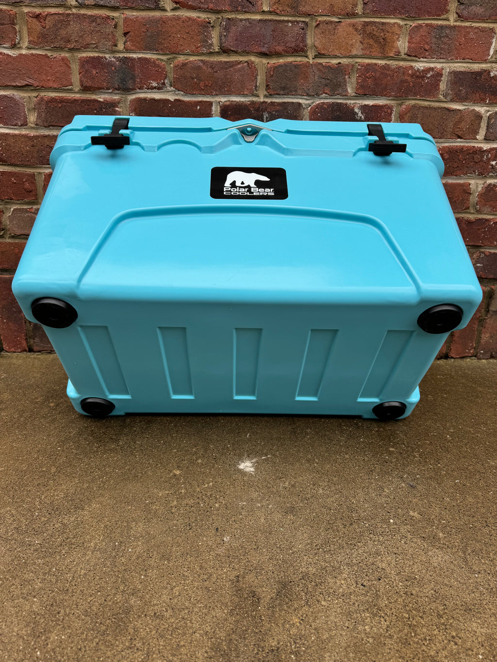 Light blue hard cooler with top carry latches and four corner wheel casters