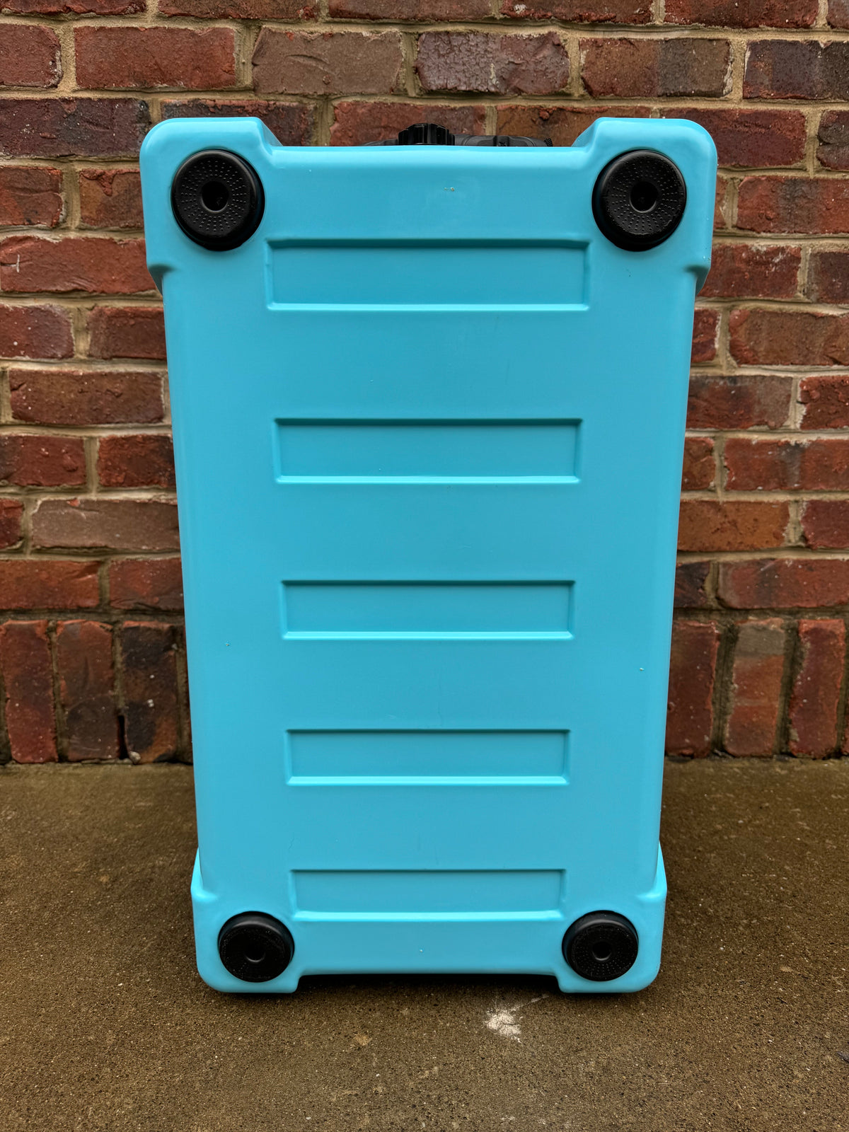 Light blue hard cooler back panel with four corner wheels and molded vents