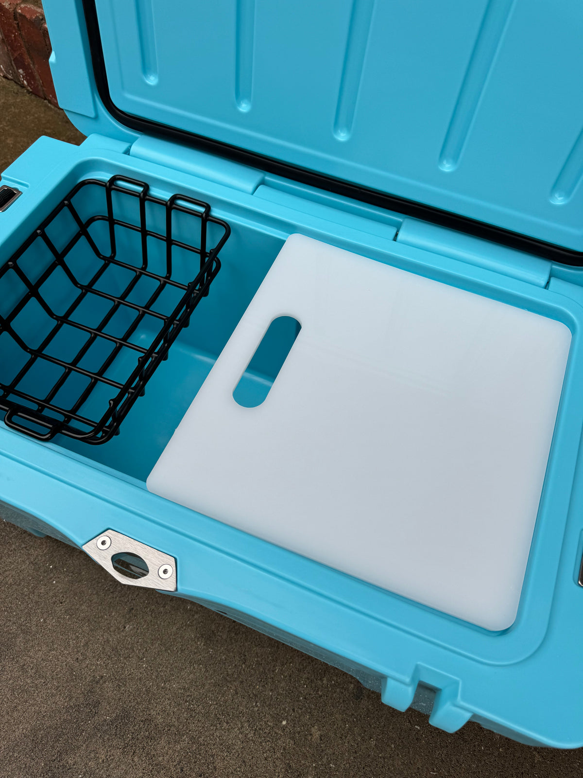 Light blue hard cooler open with white interior lid insert and molded carrying slot