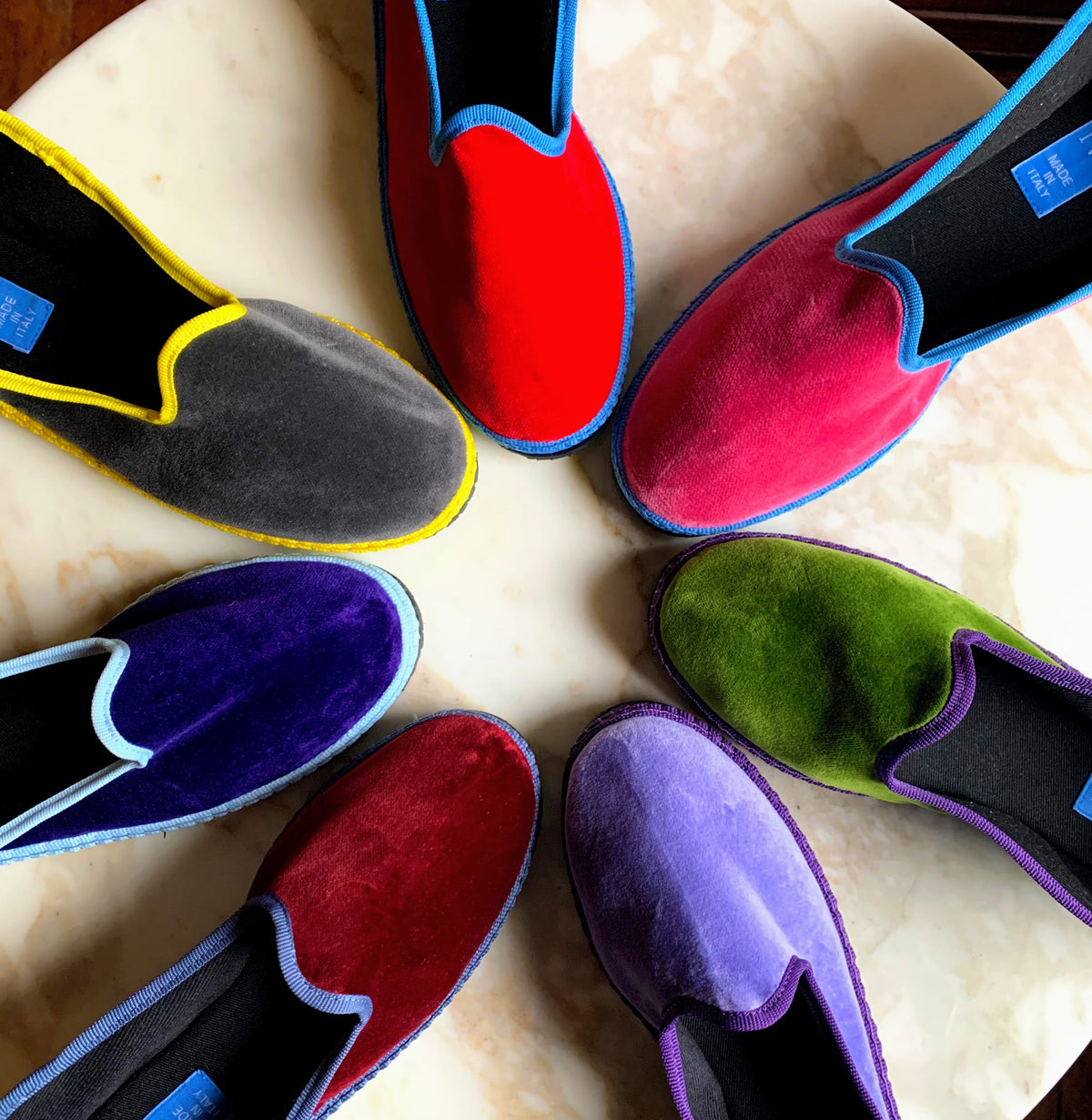Assorted suede-like slip-on slippers with contrast trim and blue tags