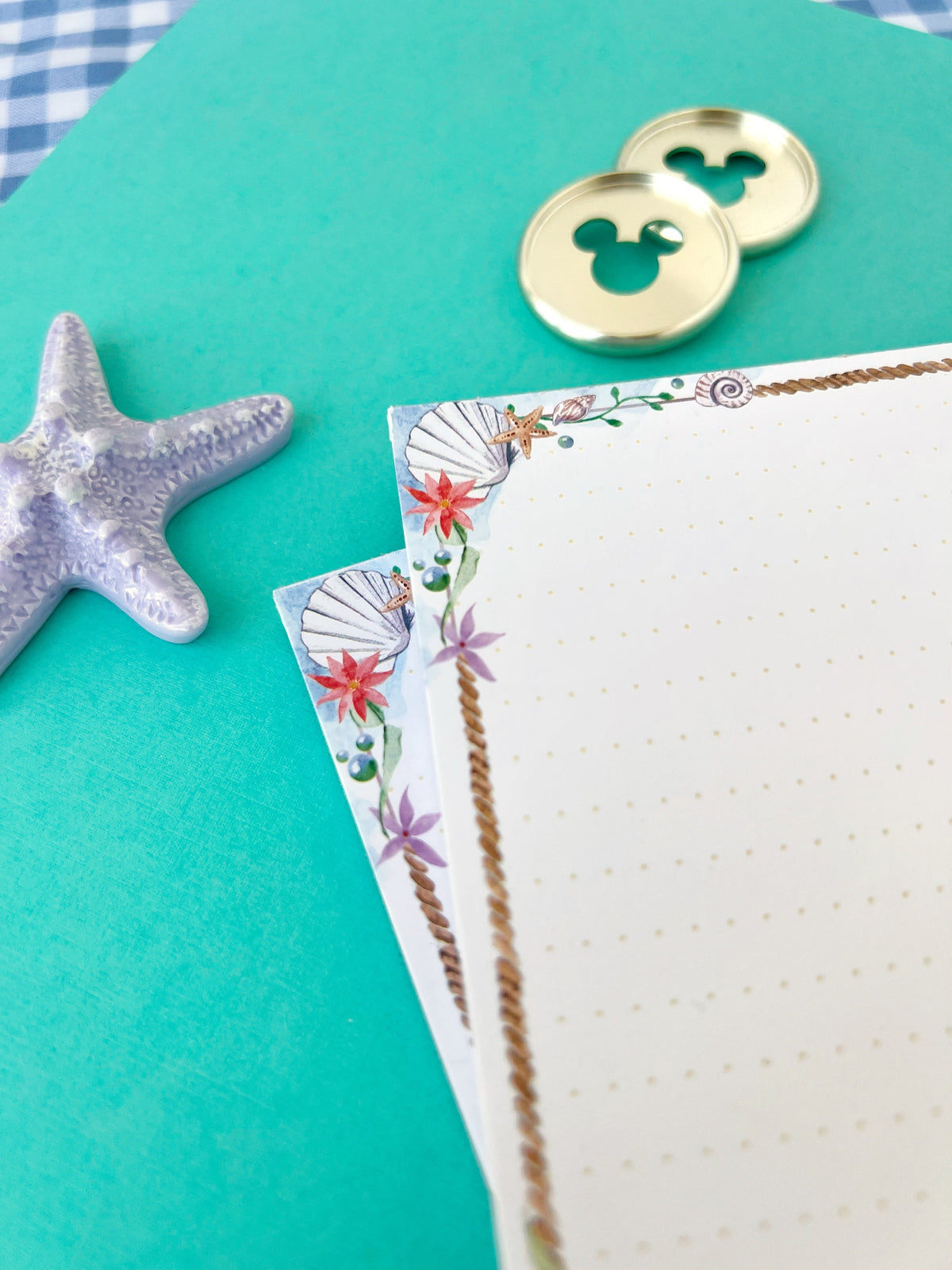 Sea-themed memo notepad page corner detail with braided frame and shell accents