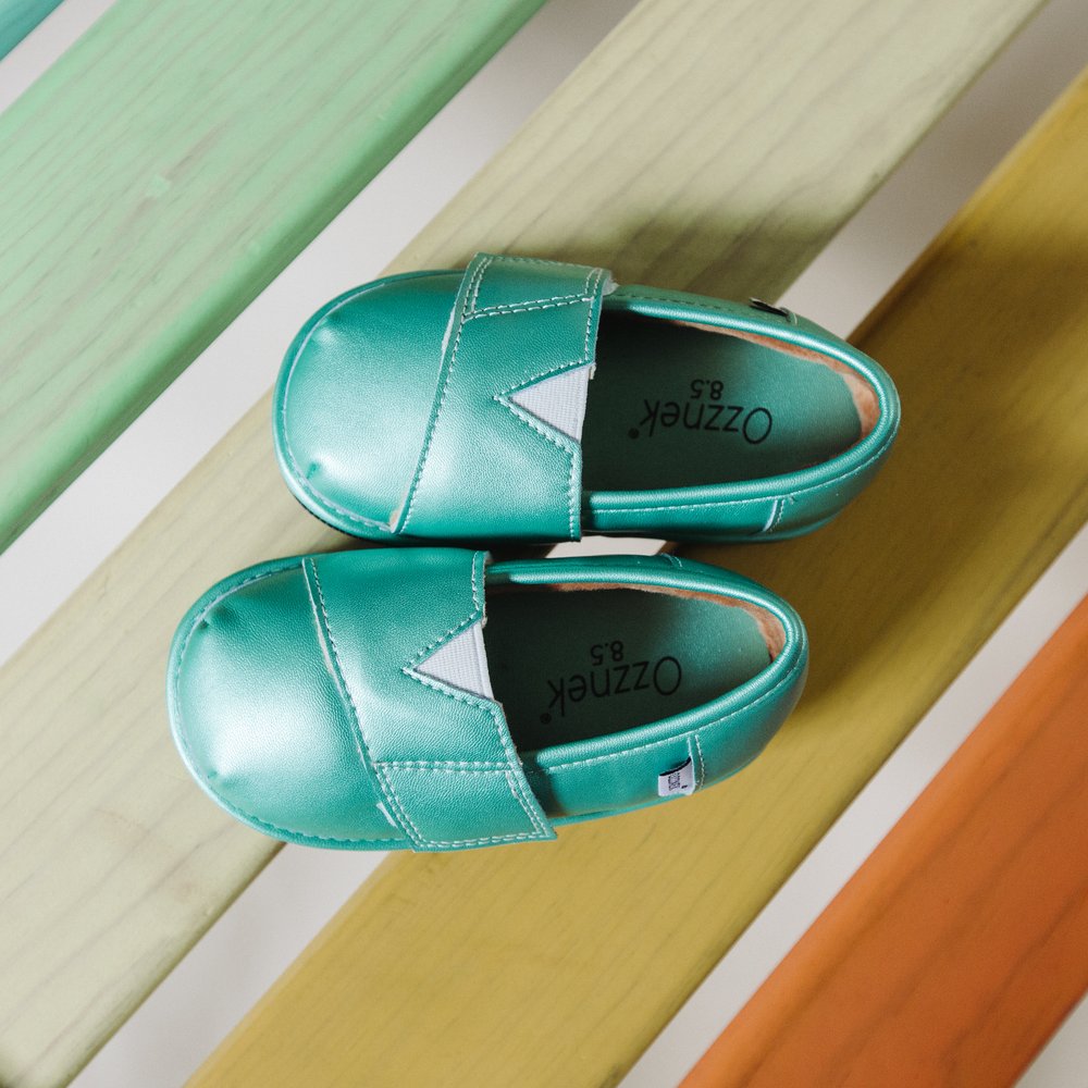 Teal slip-on barefoot shoes on wooden step, side view
