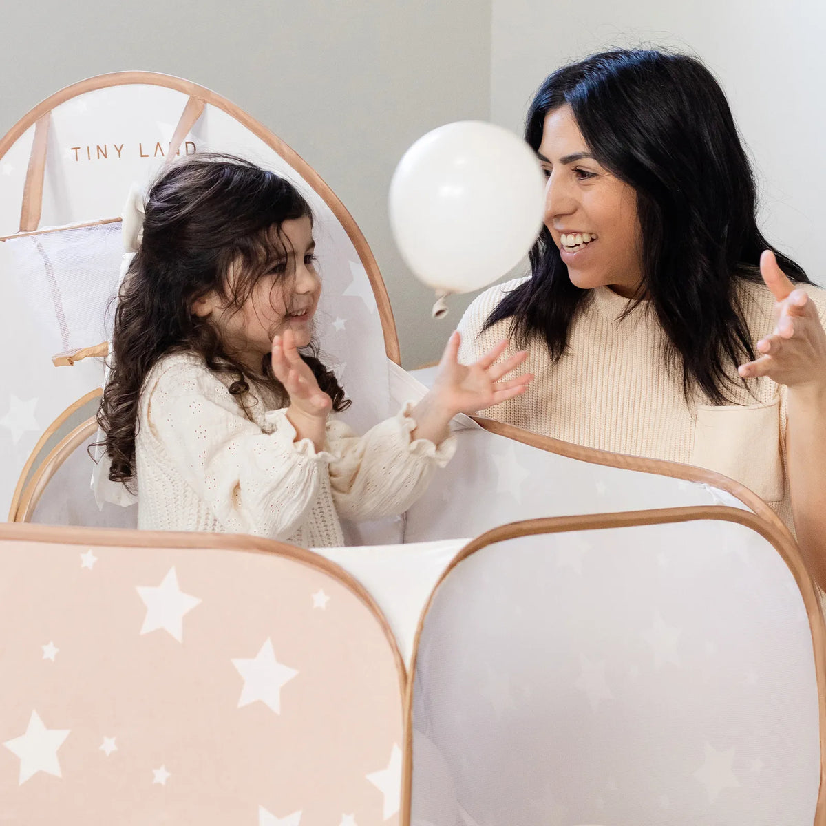Light tan star-print play tunnel with rounded viewing window, white fabric and tan trim