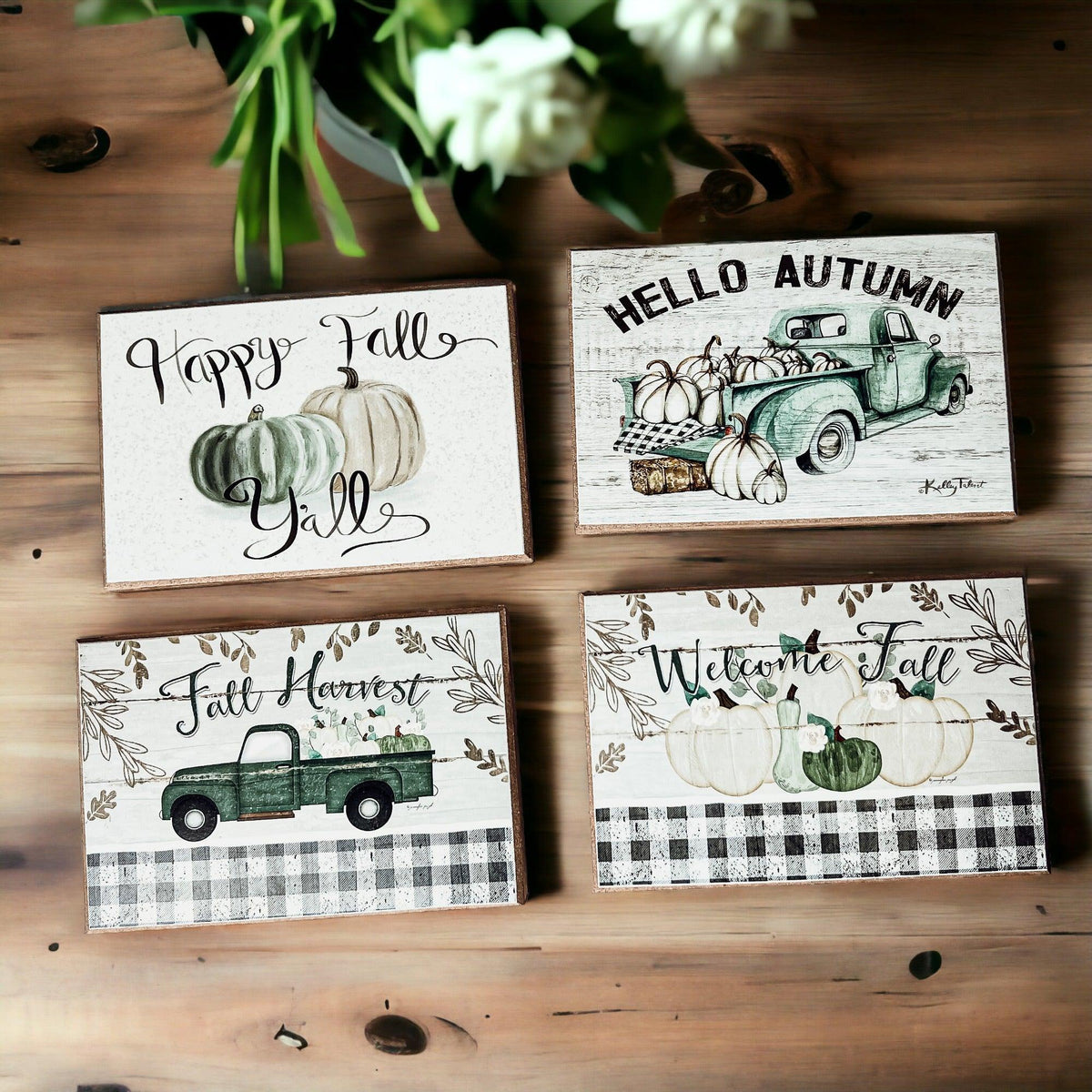 Four fall greeting cards on wood table with pumpkins and green truck illustrations