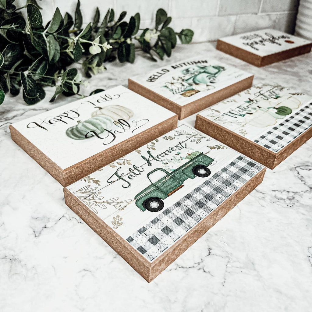 Five fall greeting cards on stone surface with pumpkins and green truck scenes