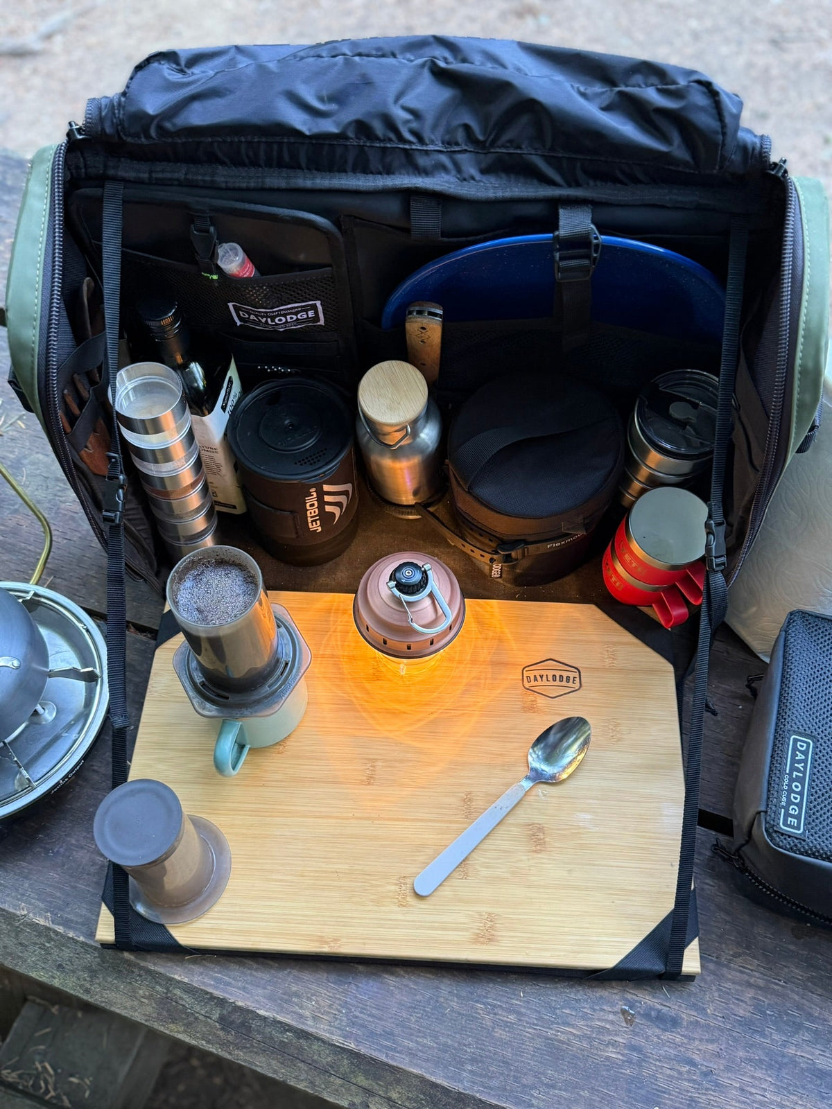 Navy camp kitchen table bag open, showing bottles, cookware, and bamboo cutting board