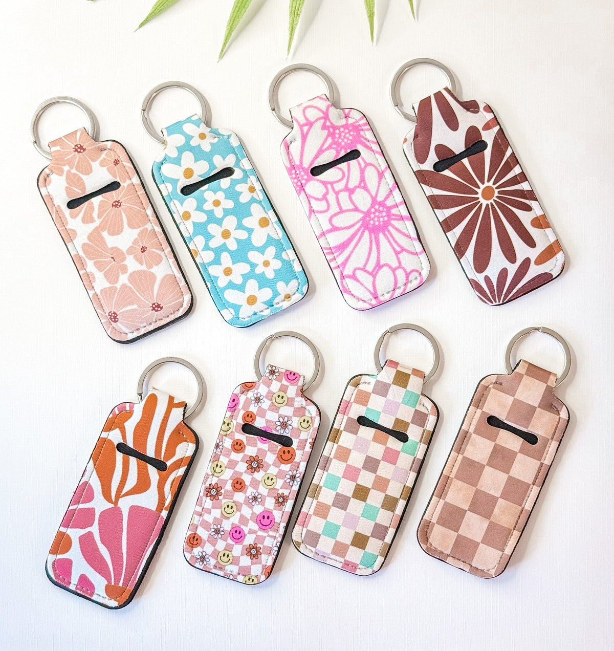 Chapstick holder keychains set with daisy, checker, and brown patterns, metal rings