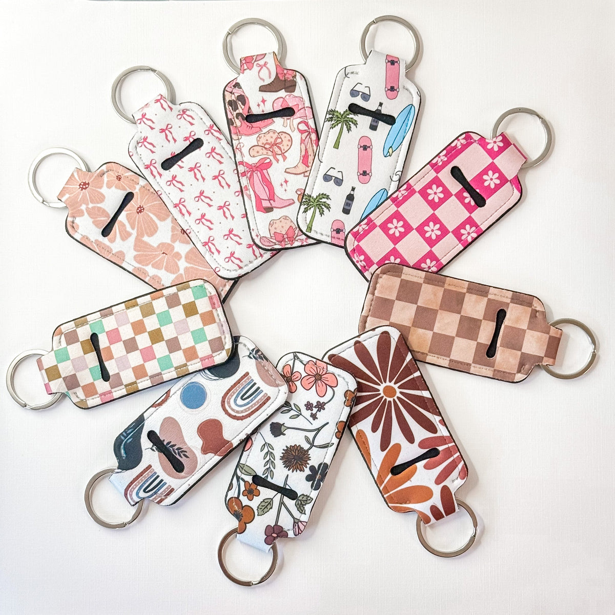 Assorted chapstick holder keychains with floral and checker patterns, metal rings