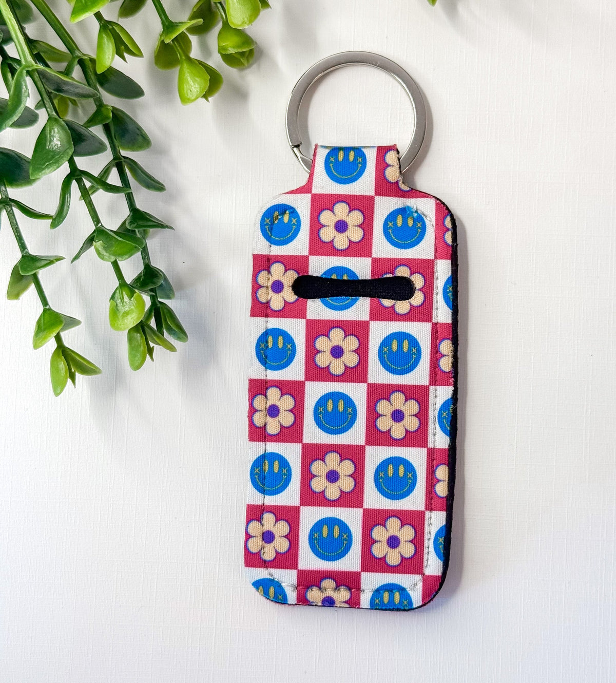 Chapstick holder keychain with blue smiley checker grid and flower motifs, key ring