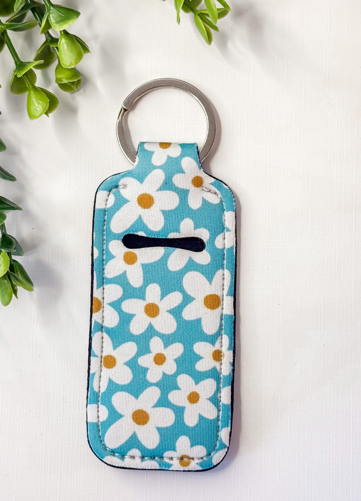 Chapstick holder keychain with light blue daisy print and black chapstick icon, ring