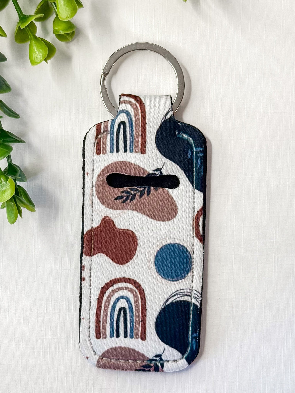 Chapstick holder keychain with whale and rainbow shapes on white fabric, metal ring