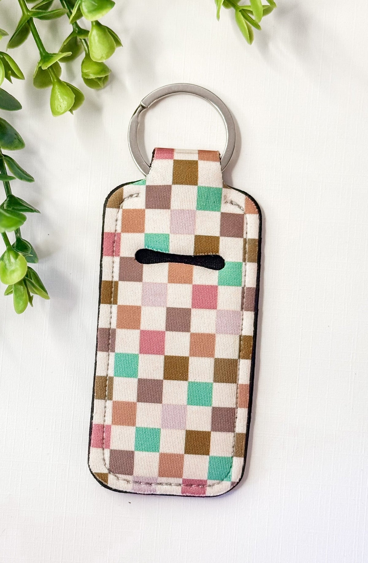 Chapstick holder keychain with multicolor checkered fabric and black chapstick icon, ring
