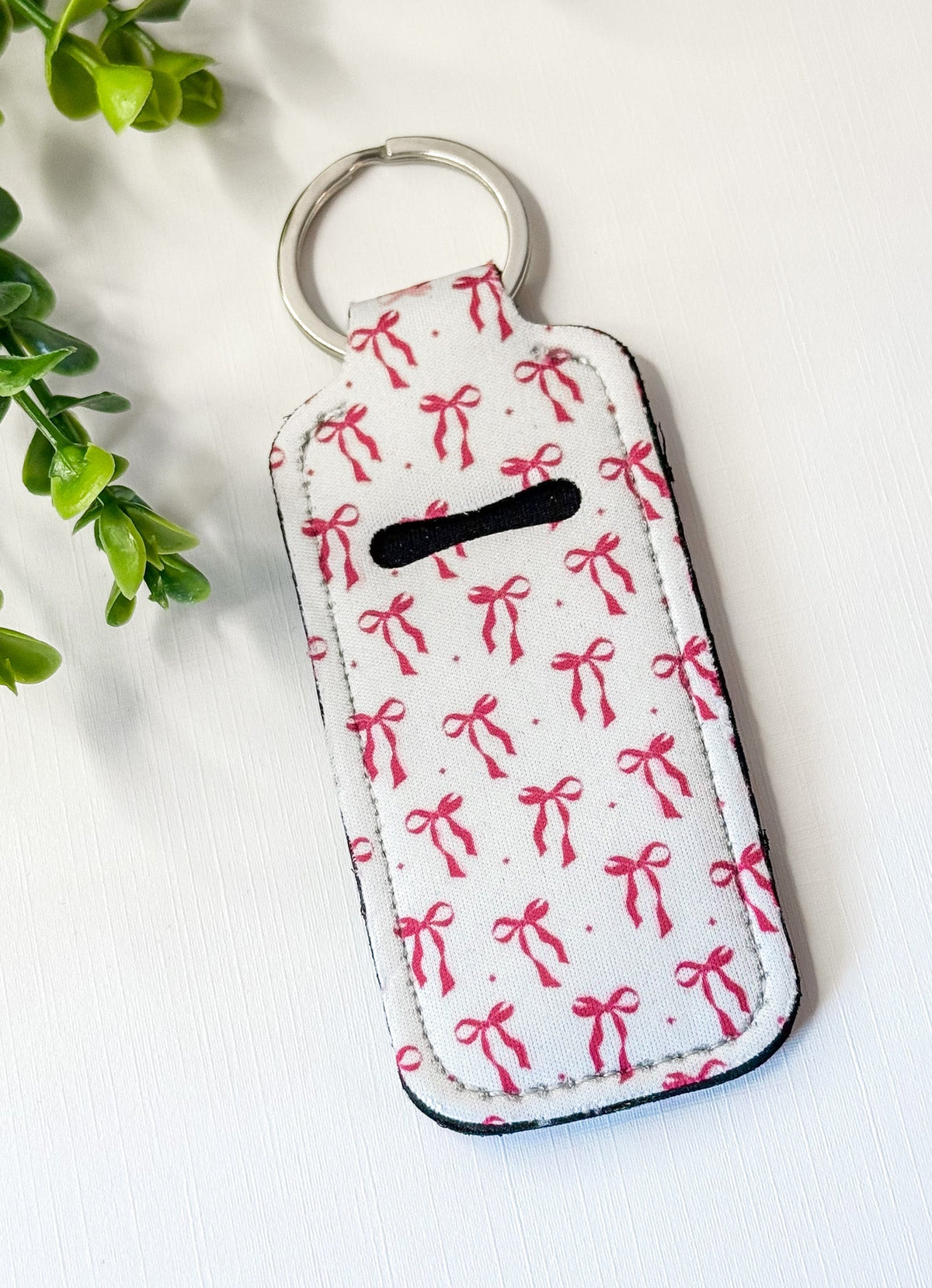 Chapstick holder keychain with white bow pattern and red bows, silver key ring