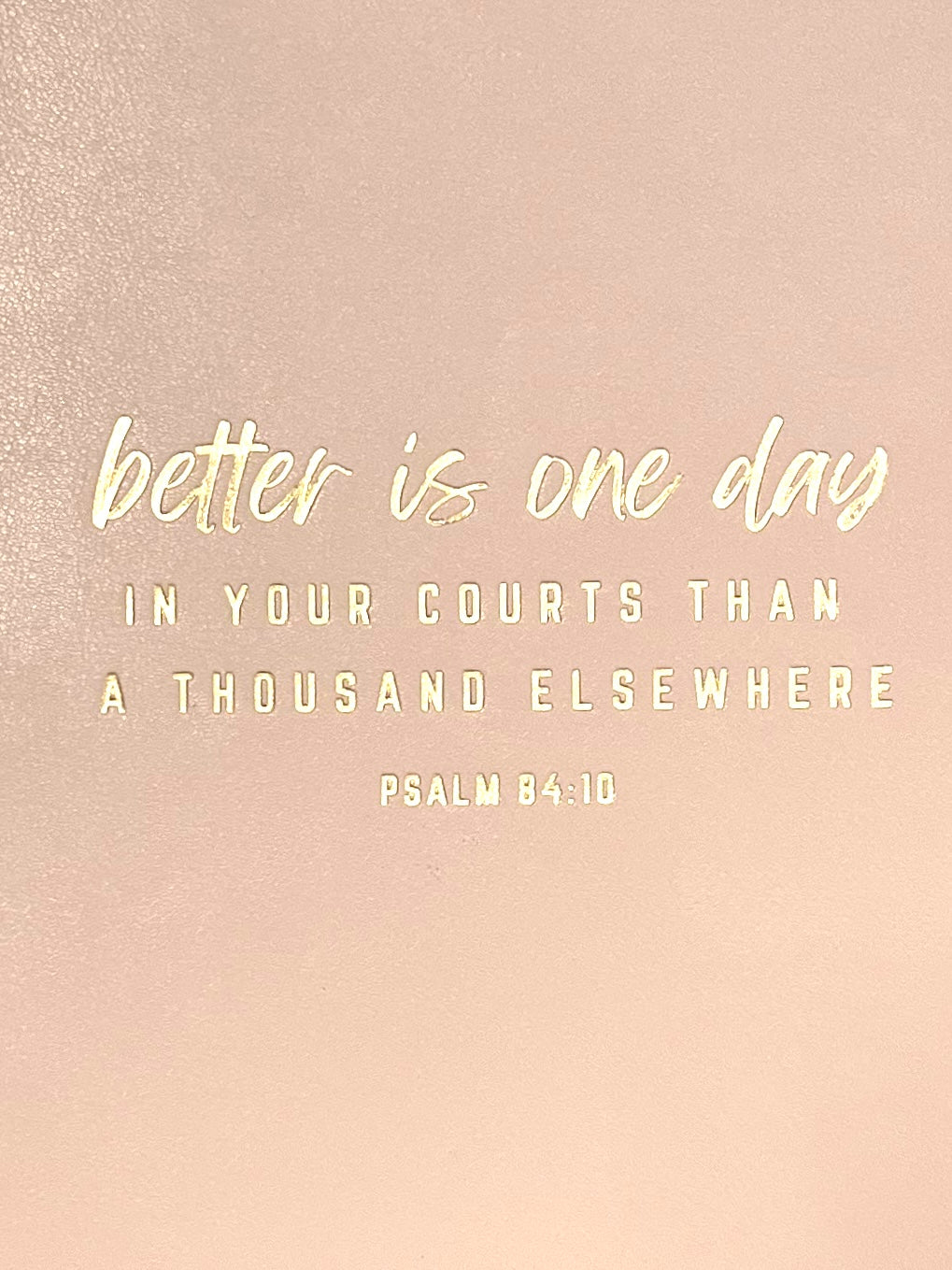 Close-up of blush pink journal cover with 'better is one day' quote and Psalm 84:10