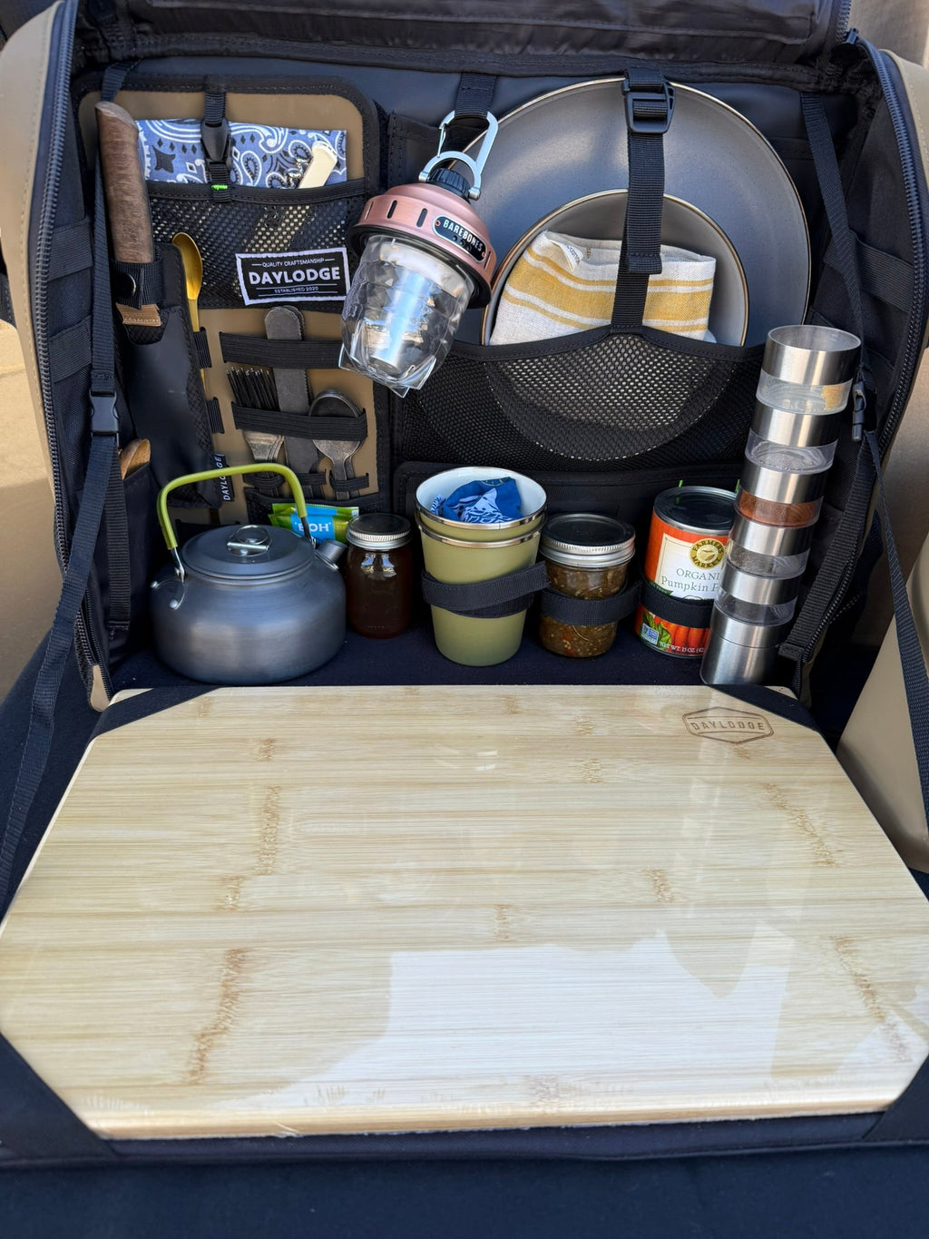 Black camp kitchen table bag open with bamboo cutting board and stored cookware