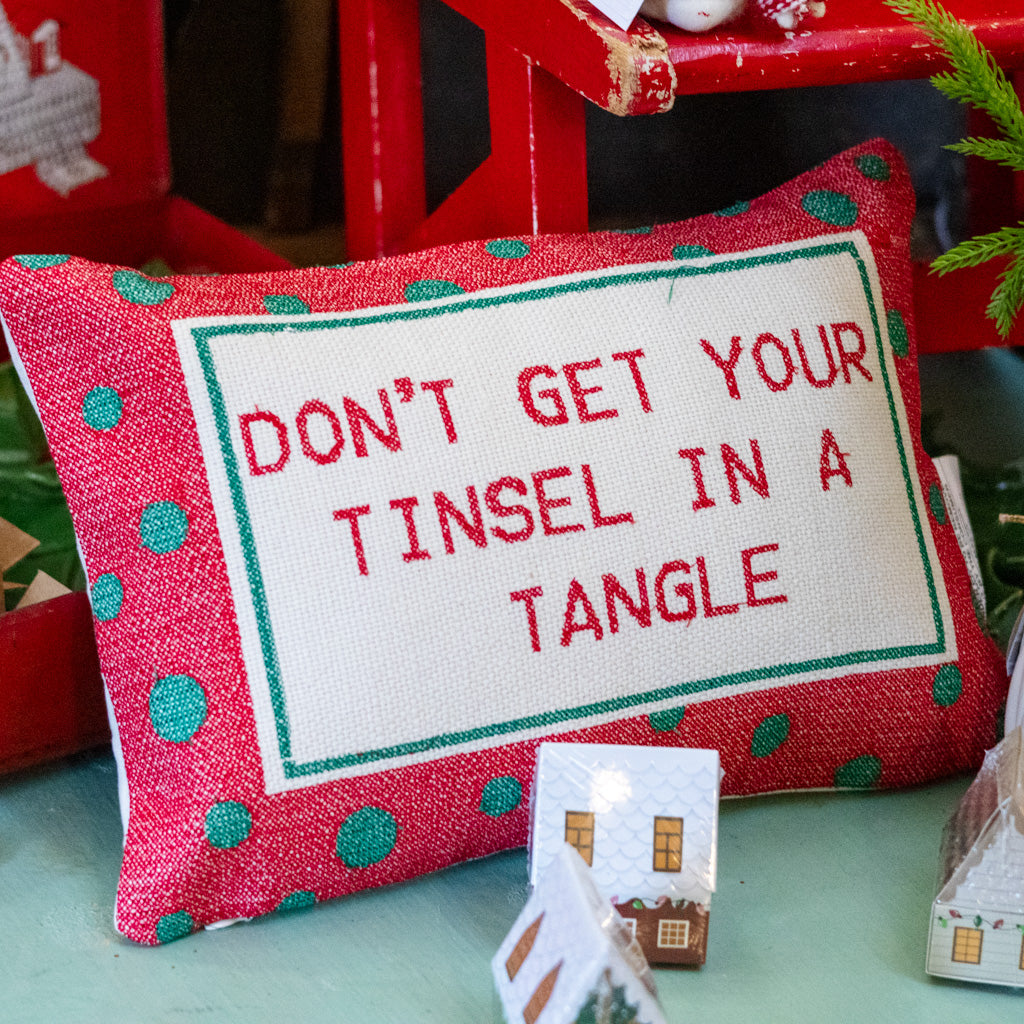 Red cotton lumbar pillow close-up with green polka dots and 'DON'T GET YOUR TINSEL IN A TANGLE' text