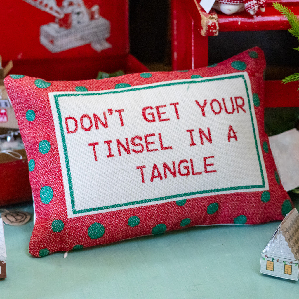 Red lumbar pillow close-up with green polka dots and 'DON'T GET YOUR TINSEL IN A TANGLE' quote