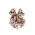 Floral football bow with tied center knot on cream fabric