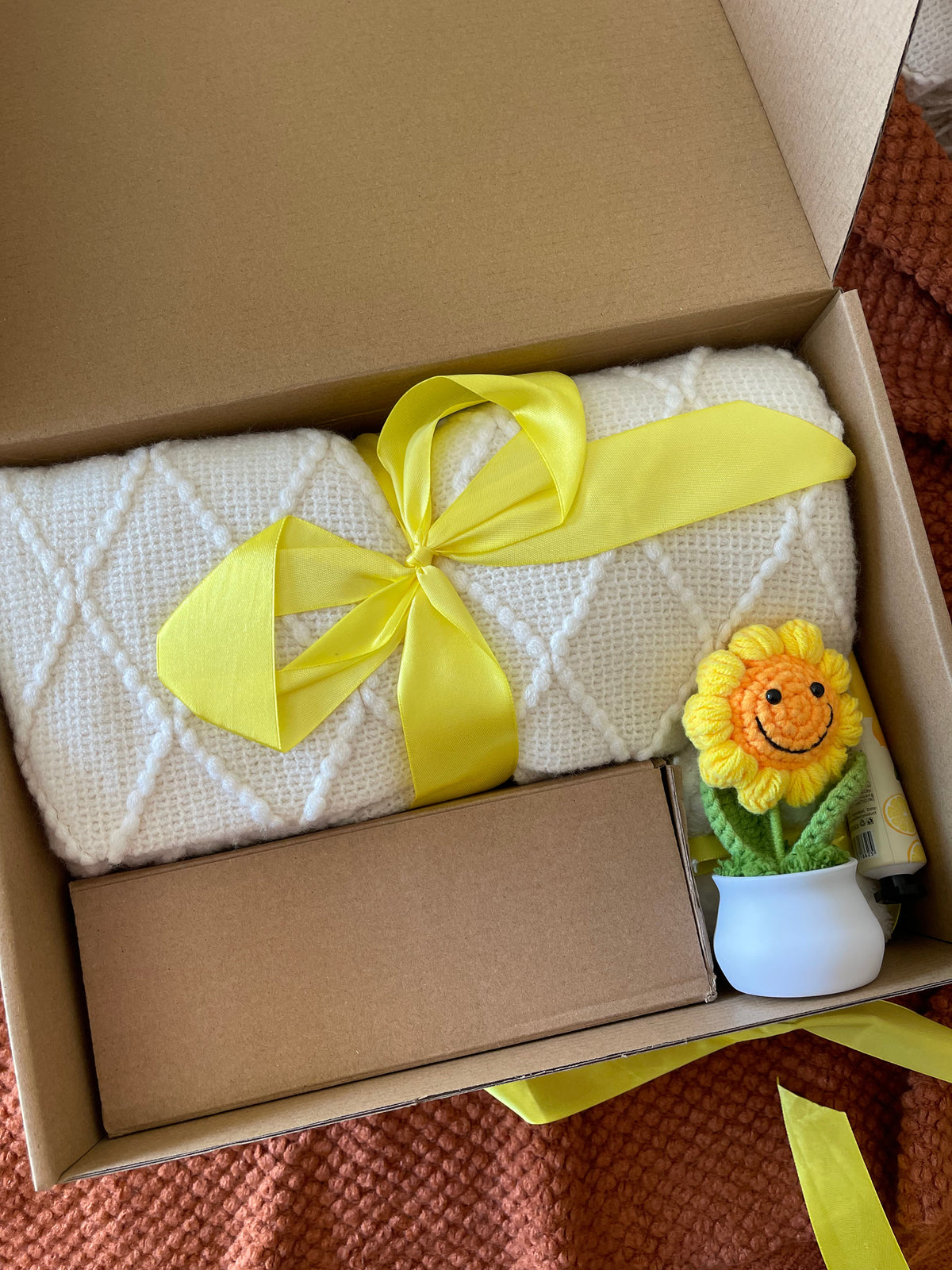 Yellow gift care package with folded white towel, bow ribbon, and small flower decor