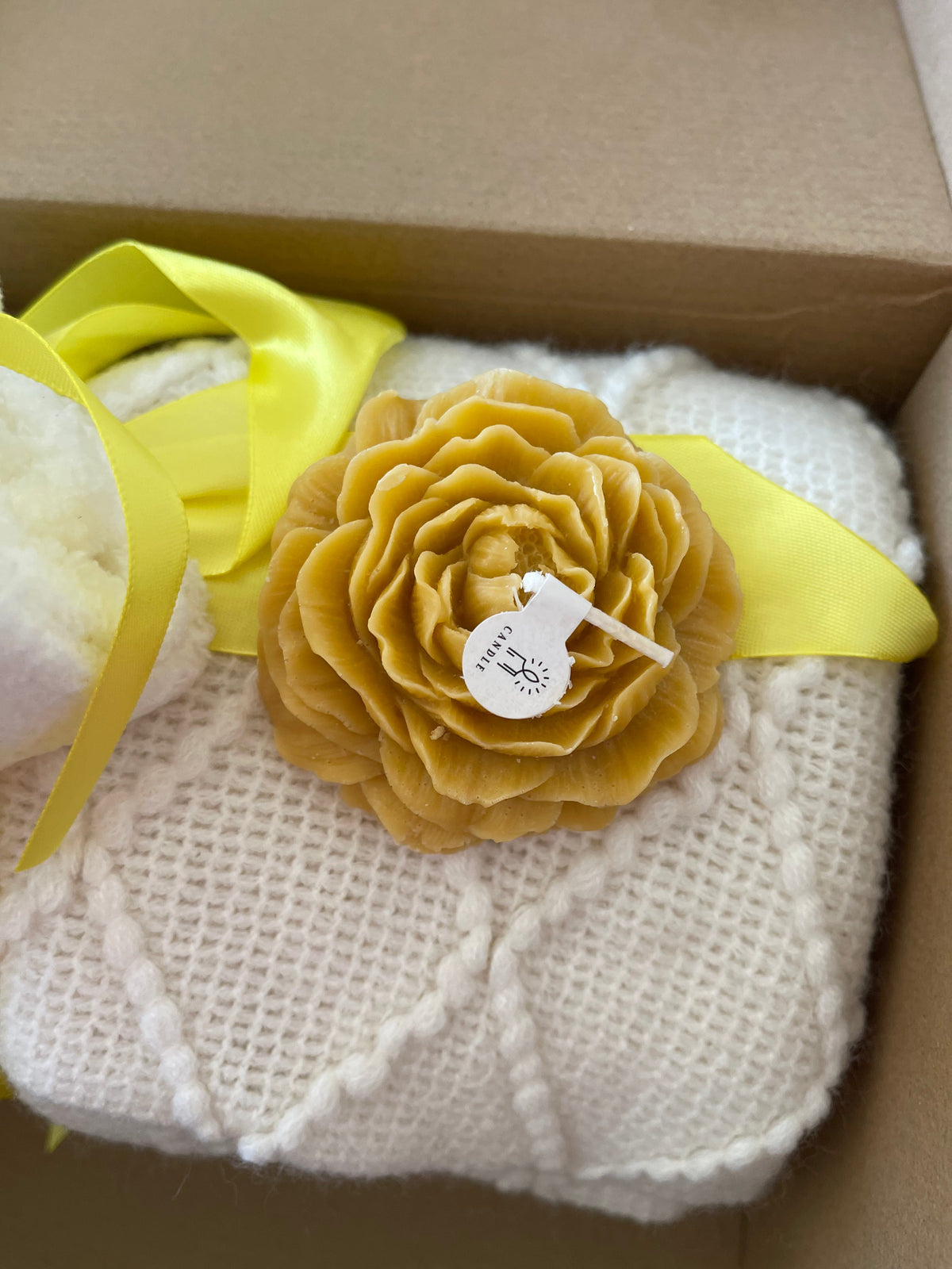 Yellow gift care package with textured flower bath scrub and ribbon tied towels