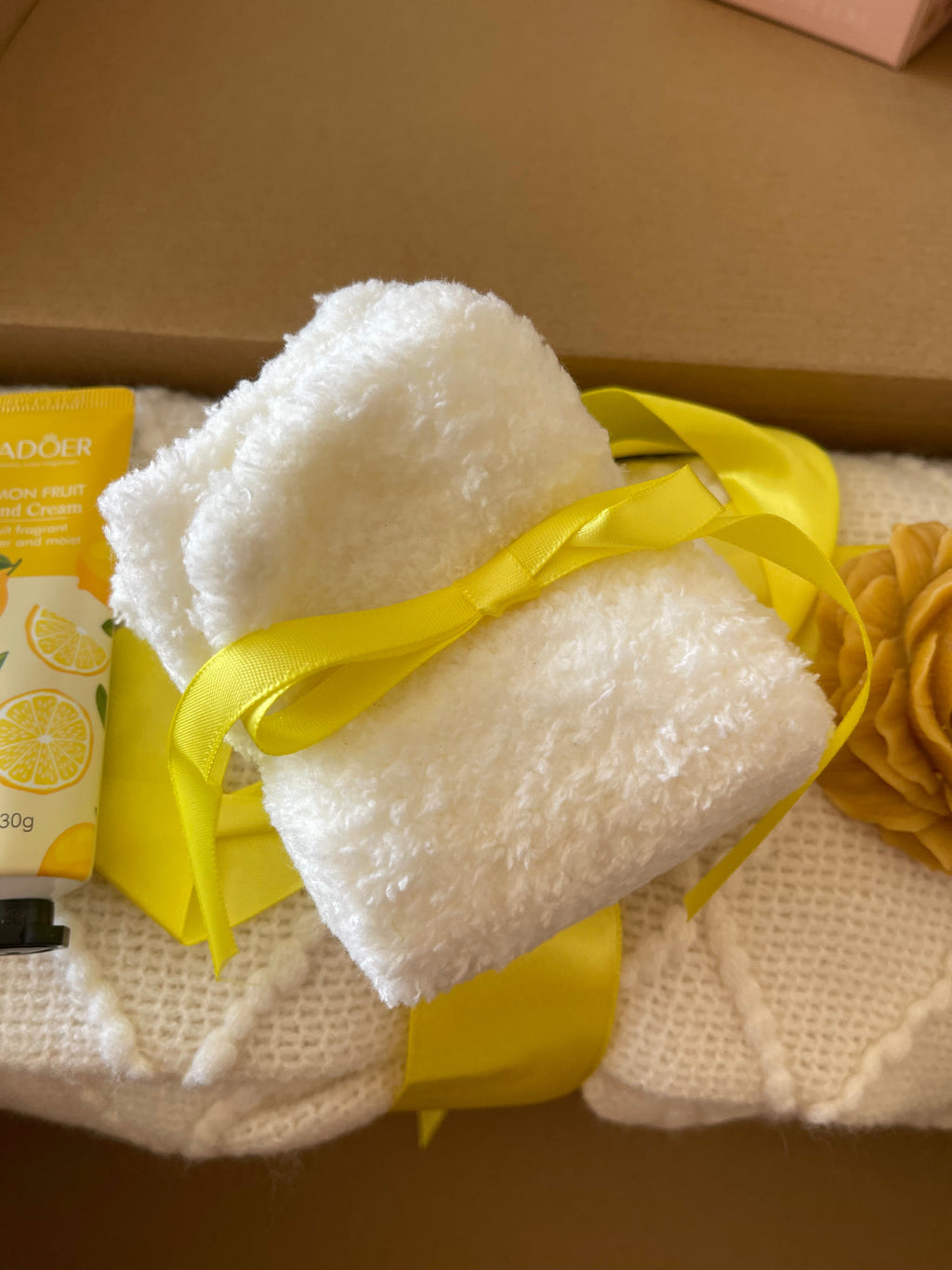 White plush bath pads tied with yellow ribbon in a yellow gift care package