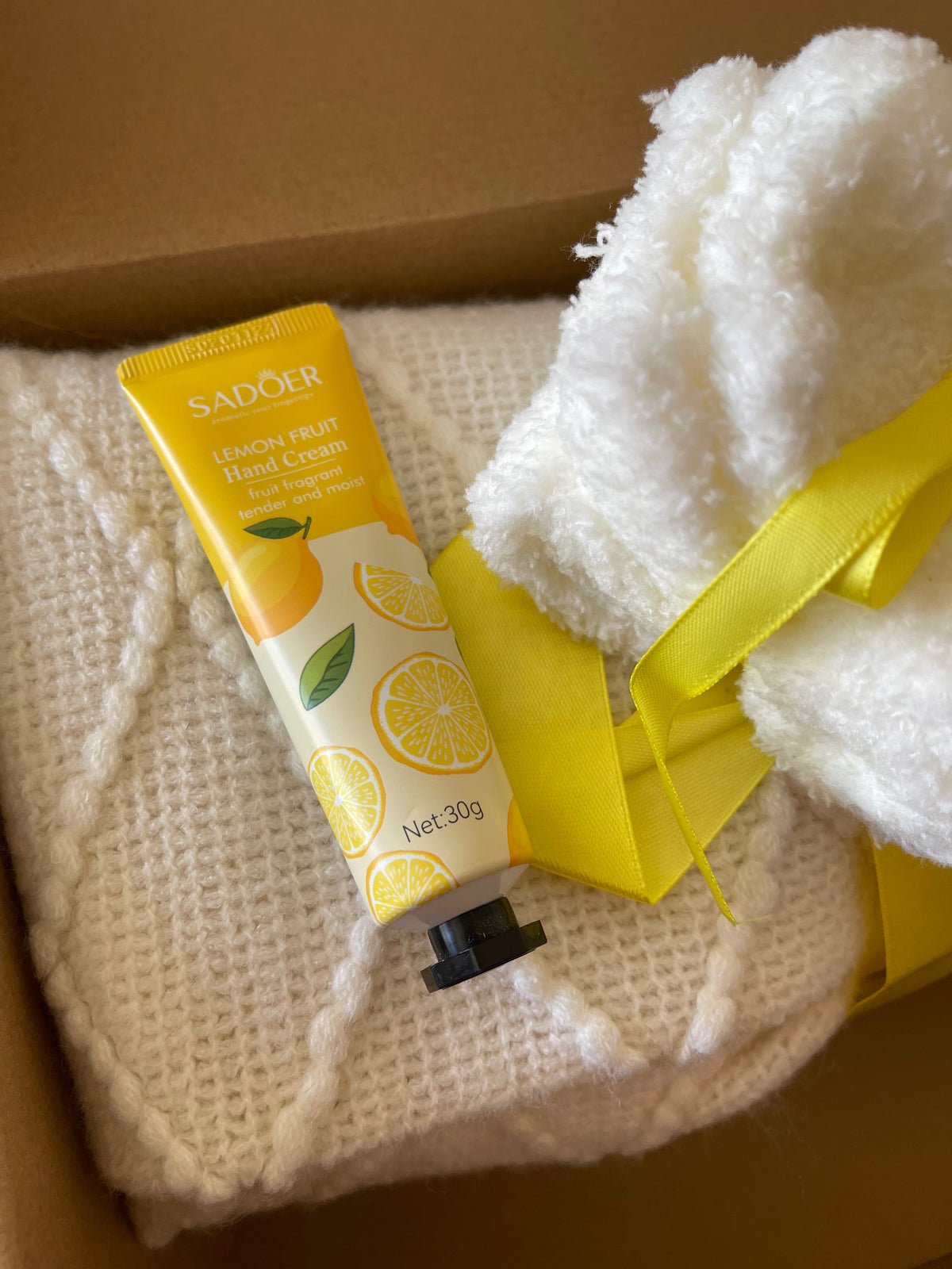 Yellow gift care package with soap tube and plush towel pads tied in ribbon