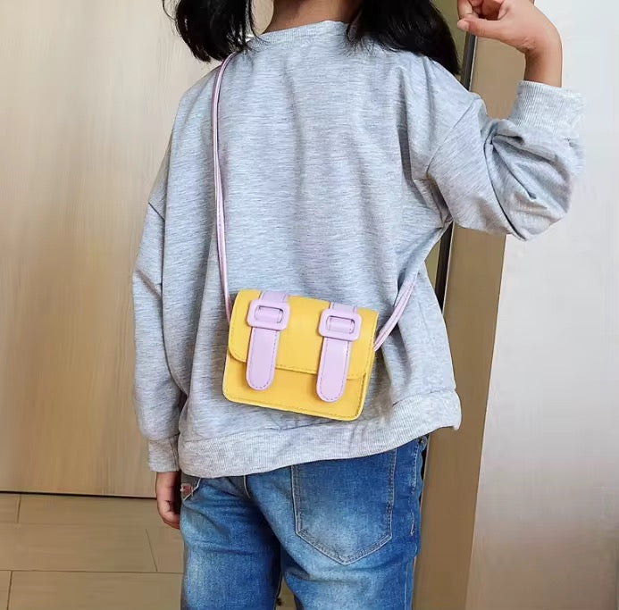 Kids mini color pop satchel bag, yellow with lavender straps worn crossbody.