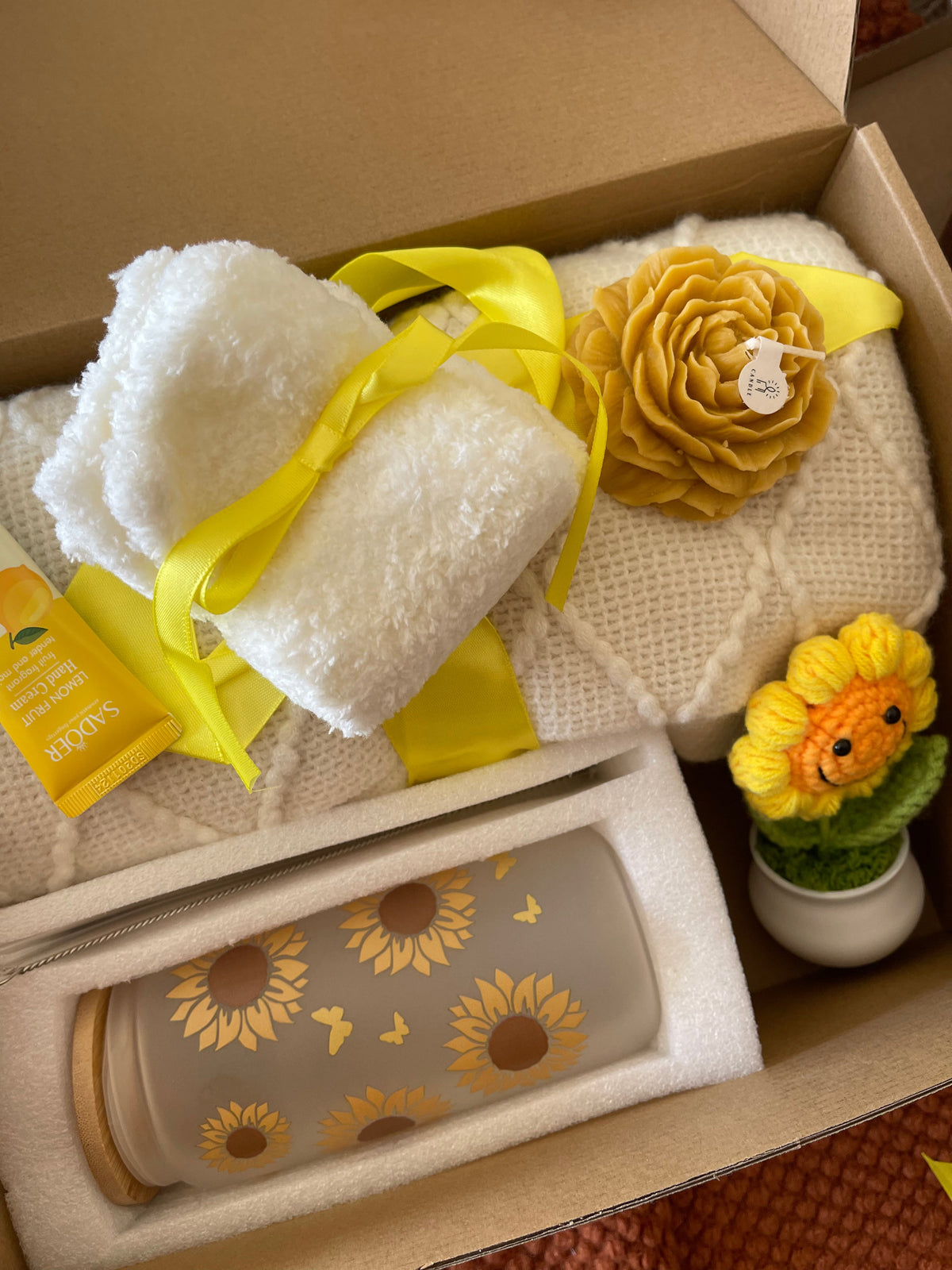 Yellow gift care package with towel pads, sunflower items, and small potted decor