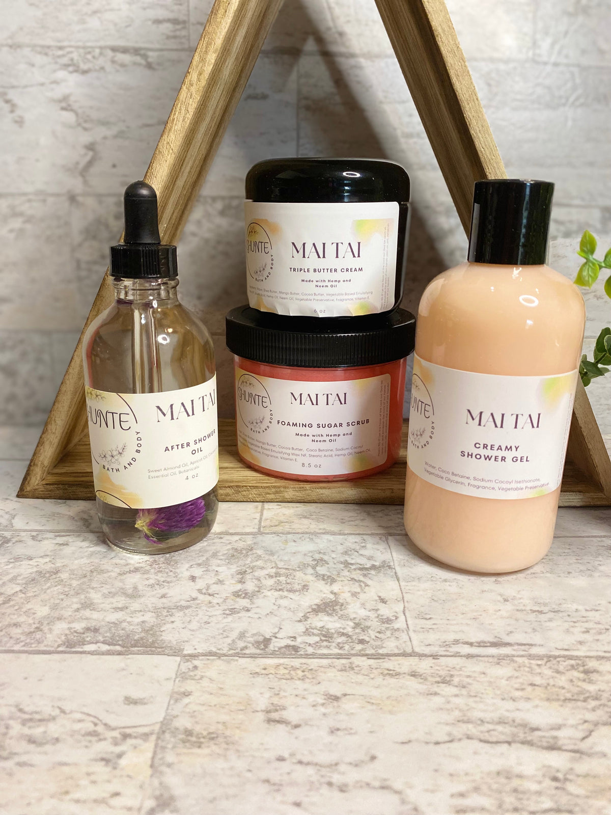 Mai Tai bath set bundle: cream scrub jar, lotion bottle, amber oil vial, and beige bottle.