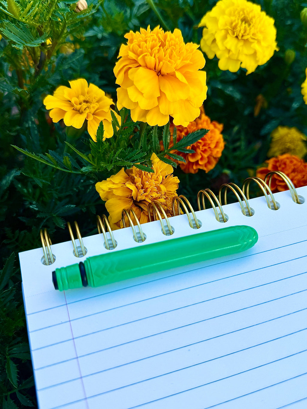 Lime green pocket pen resting on a lined notebook, cap on