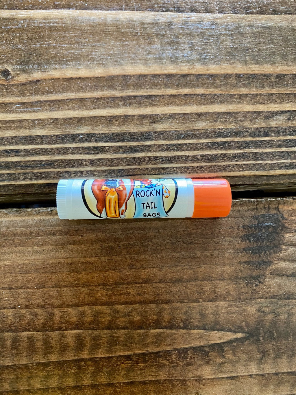 Chap-stick lip balm stick with orange cap, "Rock N Tail Bags" label